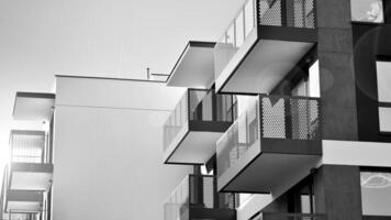 Fragment of the building's facade with windows and balconies. Modern apartment buildings on a sunny day. Facade of a modern residential building. Black and white. photo