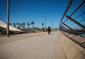 Rear view of unrecognizable person riding bicycle along the promenade marine. photo