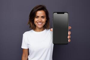 Woman in white tshirt showing blank screen smartphone on dark purple background photo