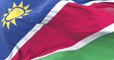 Namibia flag waving at wind in slow in blue sky, loop video