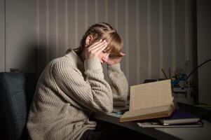 An overworked student falls asleep reading a book in the dark. Overtime processing. Study after work photo