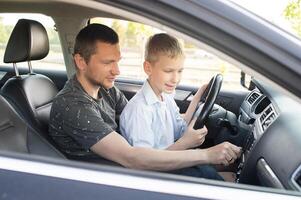 papá muestra su hijo cómo a conducir un coche. el niño es conducción con papá foto