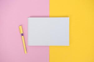 Clipboard with a white sheet and a pen on a colored background. View from above. place for text photo