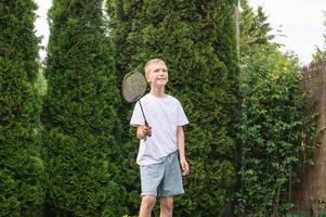 linda chico jugando bádminton en el calle. sostener un tenis raqueta en tu manos foto