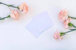 White sheets for notes lie near pink carnation flowers photo