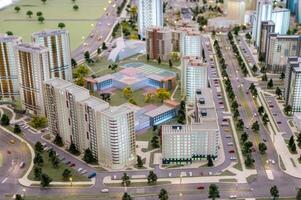 A miniature city on the table. Layout of a block with a residential building and a park. photo