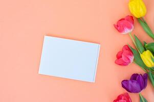 blanco blanco tarjeta con vistoso tulipanes en un rosado antecedentes. foto