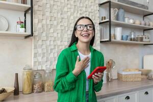Young beautiful woman in glasses and green shirt at home got a good news photo