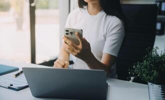 Excited happy Asian woman looking at the phone screen, celebrating an online win, overjoyed young asian female screaming with joy, isolated over a white blur background photo