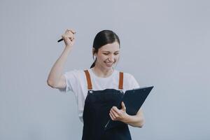 Cheerful beautiful Asian woman wearing jeans overalls with excited doing winner gesture with arms raised isolated on white background. photo