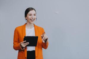 sonriente caucásico joven mujer niña persona de libre dedicación estudiante utilizando digital tableta, teniendo idea, señalando hacia arriba en espacio de copia, surf en social medios de comunicación, móvil aplicaciones, e-learning aislado en blanco foto