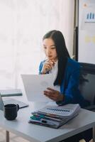 Young beautiful hispanic woman business worker using laptop reading document at office photo