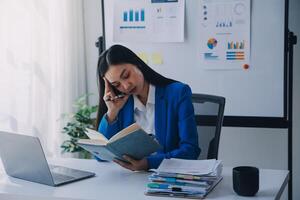 asiático mujer sensación migraña cabeza tensión.con exceso de trabajo mujer de negocios financiero mientras trabajando en ordenador portátil y tableta a moderno oficina. foto