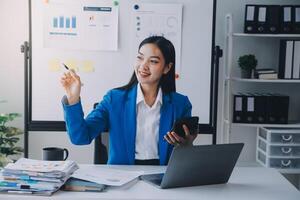 Cheerful business lady working on laptop in office, Asian happy beautiful businesswoman in formal suit work in workplace. Attractive female employee office worker smile. photo