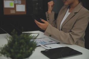 Young happy business woman, smiling pretty professional businesswoman worker looking at smartphone using cellphone mobile technology working at home or in office checking cell phone sitting at desk. photo