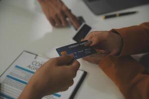 auto business, sale and people concept - close up of customer giving credit card to car dealer in auto show or salon photo