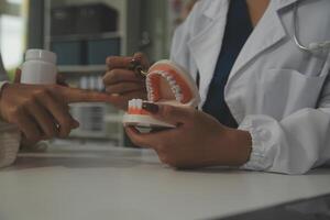 Concentrated dentist sitting at table with jaw samples tooth model and working with tablet and laptop in dental office professional dental clinic. medical doctor working photo