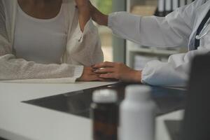 Doctor giving hope. Close up shot of young female physician leaning forward to smiling elderly lady patient holding her hand in palms. Woman caretaker in white coat supporting encouraging old person photo