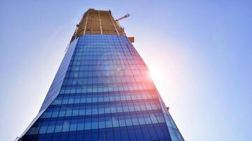 High rise building under construction. Installation of glass facade panels on a reinforced concrete structure. photo