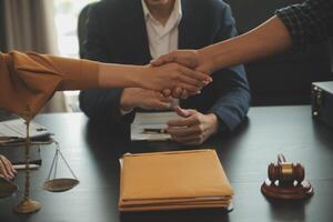 Justice and Law concept. Legal counsel presents to the client a signed contract with gavel and legal law or legal having team meeting at law firm in background photo