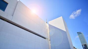 Sunlight and shadow on surface of white Concrete Building wall against blue sky background, Geometric Exterior Architecture in Minimal Street photography style photo