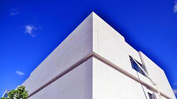 Modern white concrete building walls against blue sky. Eco architecture. Green trees and concrete office building. The harmony of nature and modernity. photo