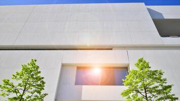 Modern white concrete building walls against blue sky. Eco architecture. Green trees and concrete office building. The harmony of nature and modernity. photo