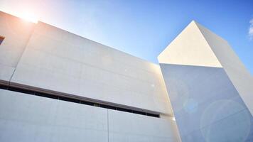 Sunlight and shadow on surface of white Concrete Building wall against blue sky background, Geometric Exterior Architecture in Minimal Street photography style photo