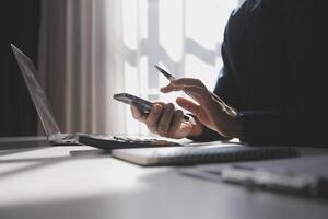 lado ver Disparo de un del hombre manos utilizando inteligente teléfono en interior, posterior ver de negocio hombre manos ocupado utilizando célula teléfono a oficina escritorio, joven masculino estudiante mecanografía en teléfono sentado a de madera mesa, llamarada foto