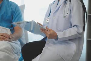 joven médico es utilizando un estetoscopio escucha a el latido del corazón de el paciente. Disparo de un hembra médico dando un masculino paciente un cheque arriba foto