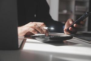 businessman working on desk office with using a calculator to calculate the numbers, finance accounting concept photo
