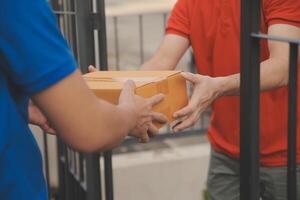 asiático entrega Rápido mensajero joven hombre utilizar dando cajas a mujer cliente él vistiendo protector cara máscara a frente hogar foto