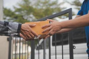 Asian delivery express courier young man use giving boxes to woman customer he wearing protective face mask at front home photo