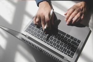 Cropped image of a young man working on his laptop in a coffee shop, rear view of business man hands busy using laptop at office desk, young male student typing on computer sitting at wooden table photo