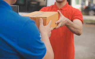 asiático entrega Rápido mensajero joven hombre utilizar dando cajas a mujer cliente él vistiendo protector cara máscara a frente hogar foto