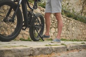 Close-up of part of a battery powered road mountain bike with a cyclist's foot on the pedal. Bike sharing city service. Ad space photo