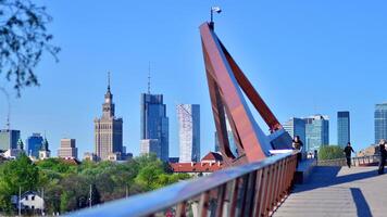 Warsaw, Poland. 11 April 2024. Bridge over the Vistula River intended only for pedestrians and cyclists. In the background, a panorama of the city with skyscrapers. photo