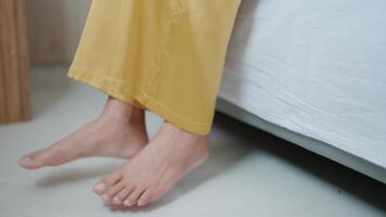 Close-up shot of a woman sitting up and getting out of bed, bare feet on the floor. video