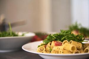 Classic Italian cuisine dish. Pasta penne with tomatoes, arugula leaves and parmesan cheese. Copy advertising space. Food background. Classic Italian cuisine dish. photo