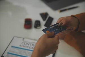 auto business, sale and people concept - close up of customer giving credit card to car dealer in auto show or salon photo