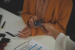 auto business, sale and people concept - close up of customer giving credit card to car dealer in auto show or salon photo
