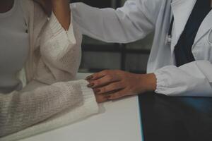 Doctor giving hope. Close up shot of young female physician leaning forward to smiling elderly lady patient holding her hand in palms. Woman caretaker in white coat supporting encouraging old person photo