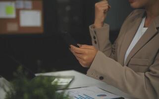 Young happy business woman, smiling pretty professional businesswoman worker looking at smartphone using cellphone mobile technology working at home or in office checking cell phone sitting at desk. photo
