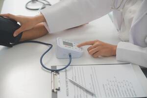 Male doctor uses a blood pressure monitor to check the body pressure and pulse of the patients who come to the hospital for check-ups, Medical treatment and health care concept. photo