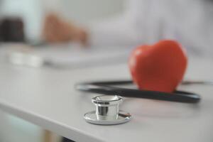 Hands of doctor woman holding red heart, showing symbol of love, human support to patient, promoting medical insurance, early checkup for healthcare, cardiologist help. Close up of object photo