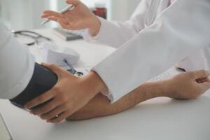 Male doctor uses a blood pressure monitor to check the body pressure and pulse of the patients who come to the hospital for check-ups, Medical treatment and health care concept. photo