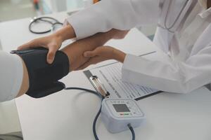 Male doctor uses a blood pressure monitor to check the body pressure and pulse of the patients who come to the hospital for check-ups, Medical treatment and health care concept. photo