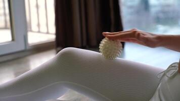 Athletic slim caucasian woman doing thigh self-massage with a massage ball indoors. Self-isolating massage photo