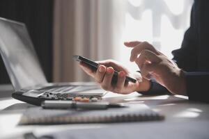 lado ver Disparo de un del hombre manos utilizando inteligente teléfono en interior, posterior ver de negocio hombre manos ocupado utilizando célula teléfono a oficina escritorio, joven masculino estudiante mecanografía en teléfono sentado a de madera mesa, llamarada foto