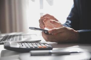 Side view shot of a man's hands using smart phone in interior, rear view of business man hands busy using cell phone at office desk, young male student typing on phone sitting at wooden table, flare photo